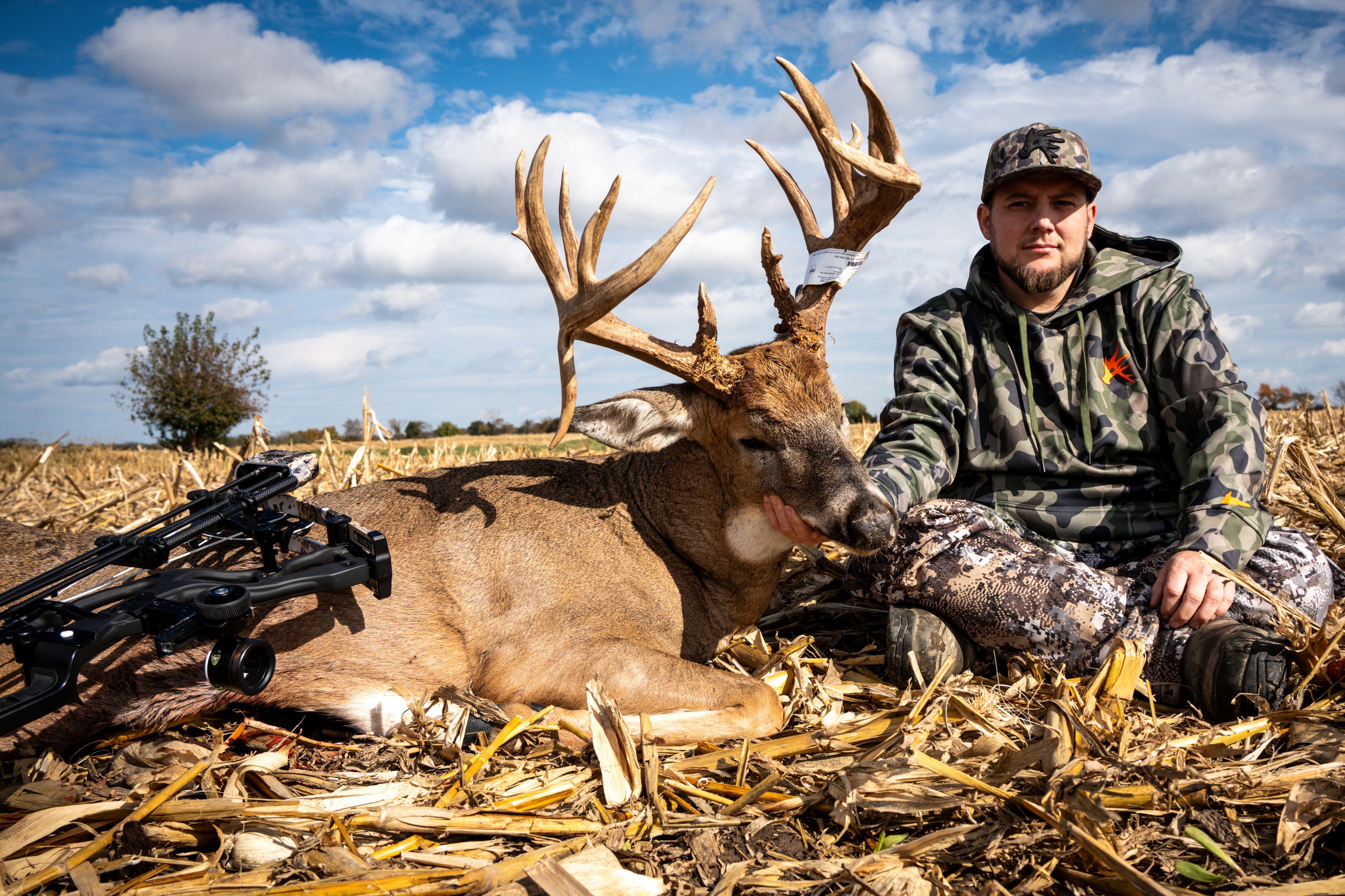 Hunter with a large deer in a field on a clear day